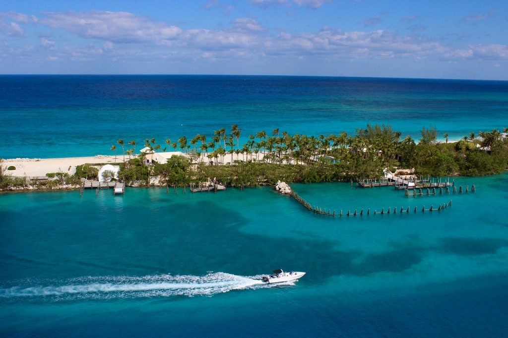 Mar azul em Nassau, com ilha de vegetação esverdeada e areia clara