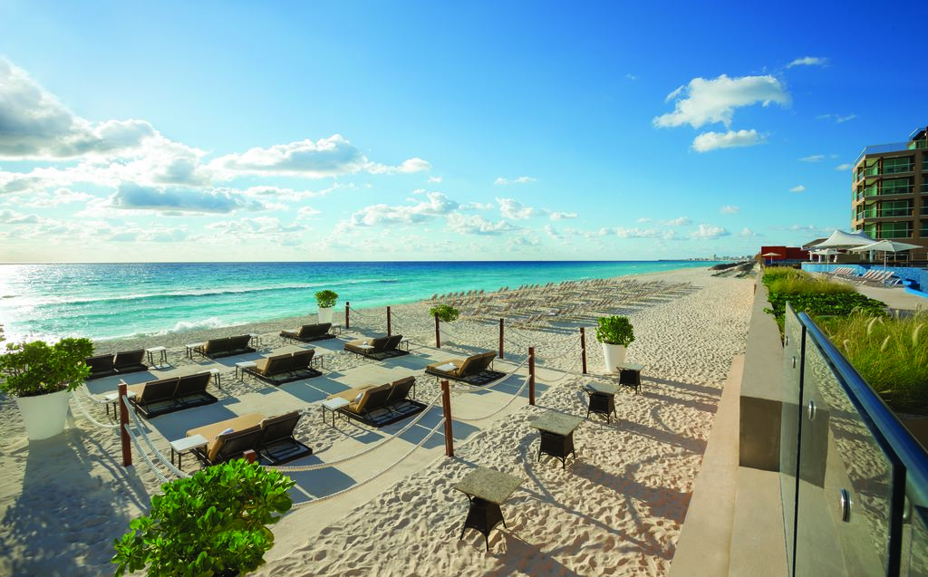 Praia do Hard Rock Hotel Cancun, com o céu azul e o mar azul-claro