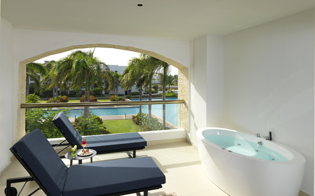 Varanda do Hard Rock Hotel & Casino Punta Cana, com duas espreguiçadeiras, banheira e a piscina ao fundo